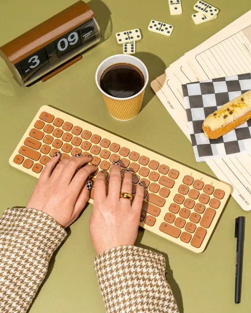 Beige & burnt-orange compact keyboard flatlay with coffee and eclair | Knotably Creative H