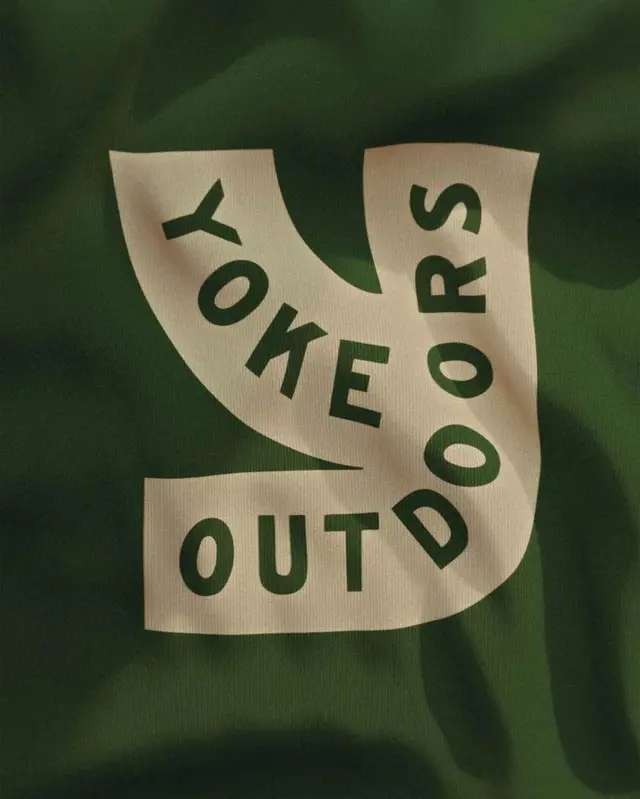 Yoke Outdoors cream 'Y' logo printed on forest‑green fabric