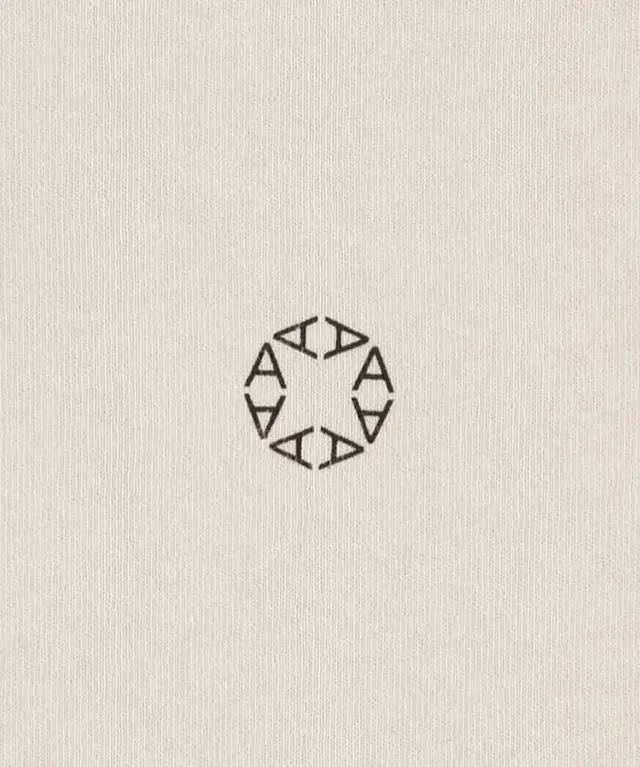 Circular ring of six stylized 'A' letters on beige linen (IMG_2494.jpg)