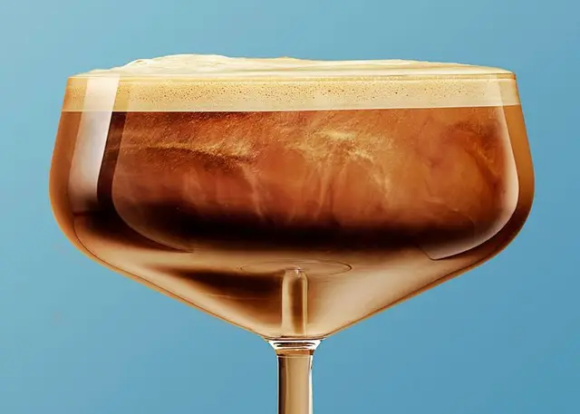 Close-up coffee cocktail in coupe glass on cyan background