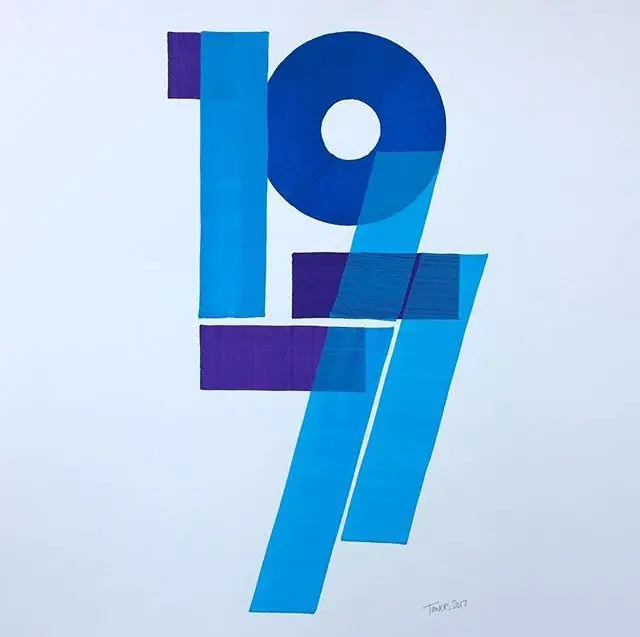 Layered geometric numerals '1977' in blue and purple on white paper