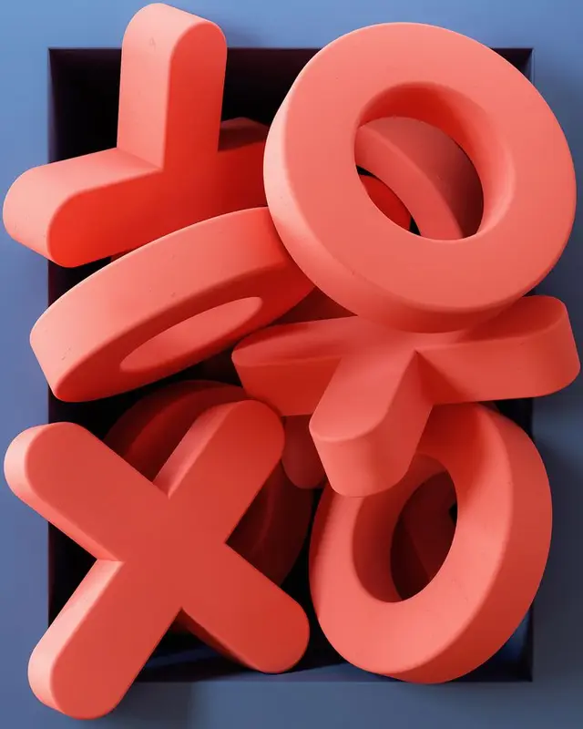Stacked coral X and O game tokens in navy square tray