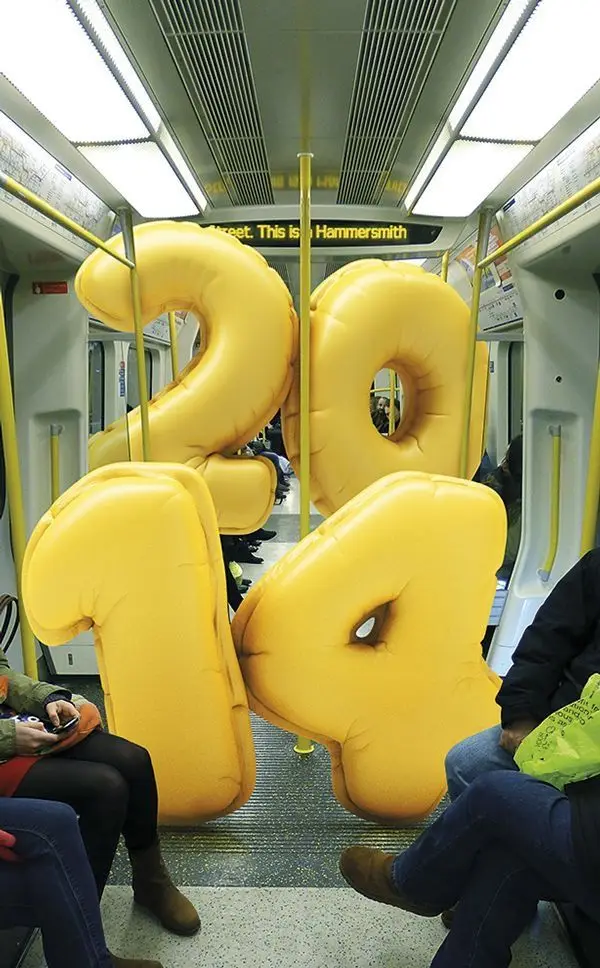 Yellow inflatable numeral balloons filling a London Underground carriage (display reads 'H