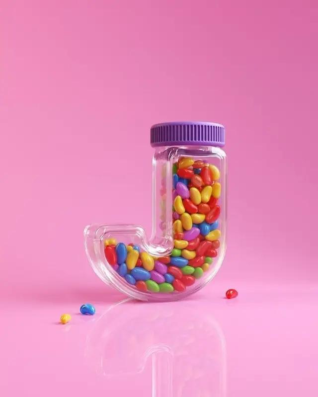 J-shaped glass jar filled with colorful jellybeans on pink background