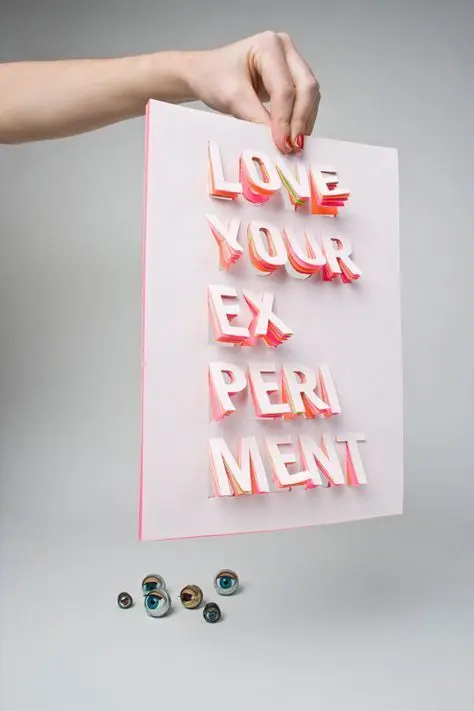 3D paper-letters poster: "LOVE YOUR EXPERIMENT" held by hand with glass marbles