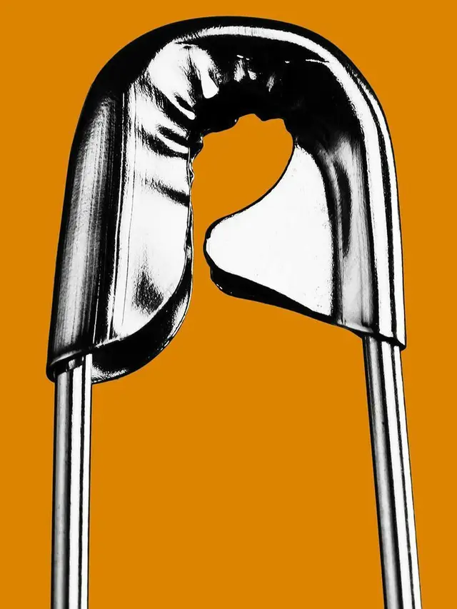 Macro of Split Chrome Safety Pin on Burnt Orange Background