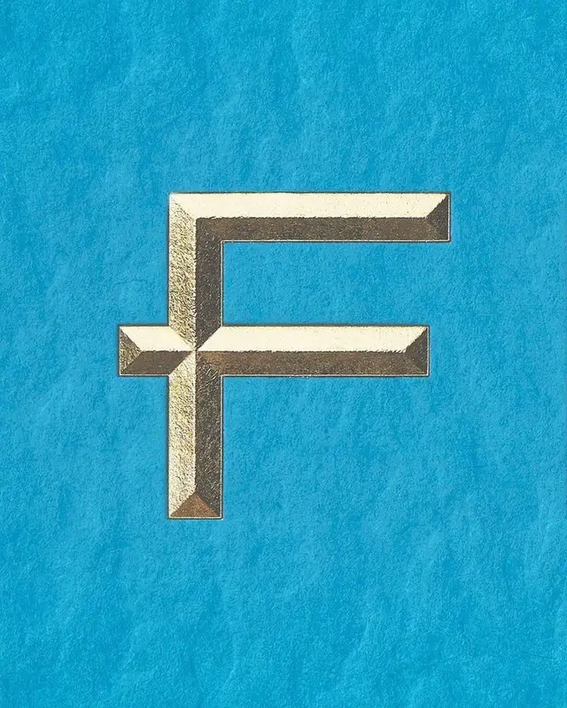 Beveled metallic gold letter "F" foil on cyan textured paper