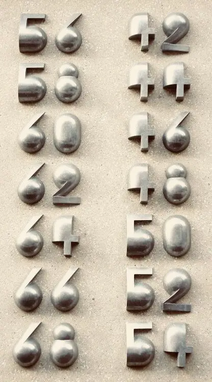 Polished chrome 3D numerals on beige plaster wall