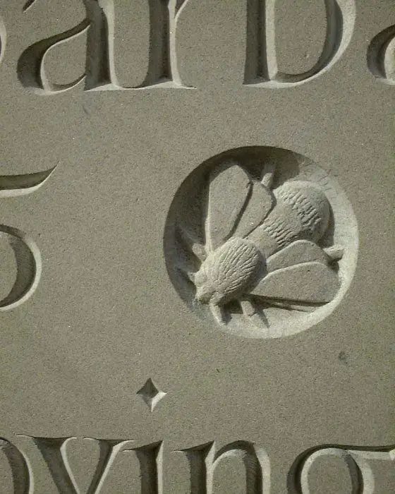 Carved stone plaque with bee medallion and Roman serif lettering