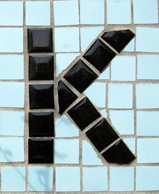 Tile mosaic letter K — black glossy squares on pale blue grid