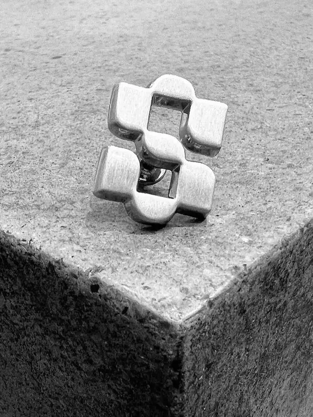Brushed silver geometric cufflink on concrete corner