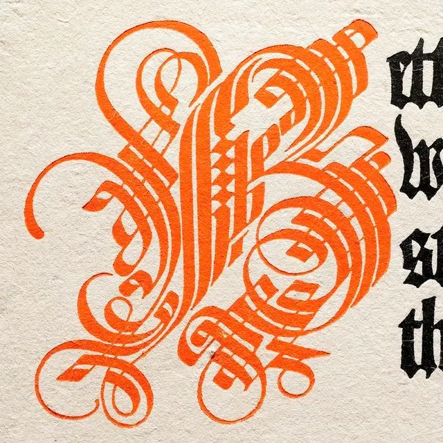 Ornate orange calligraphic initial on textured paper