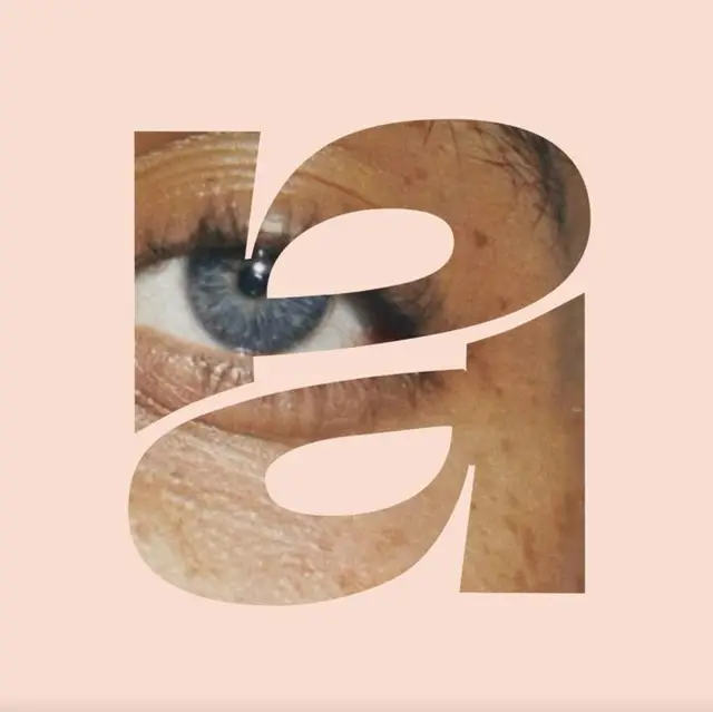 Lowercase 'a' typographic cutout with blue eye close-up on peach background
