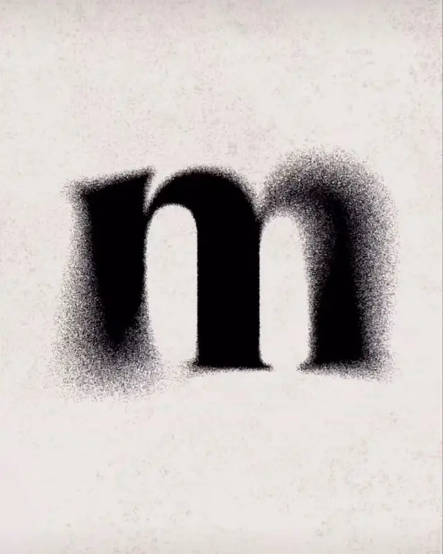 Stippled serif lowercase “m” on textured paper