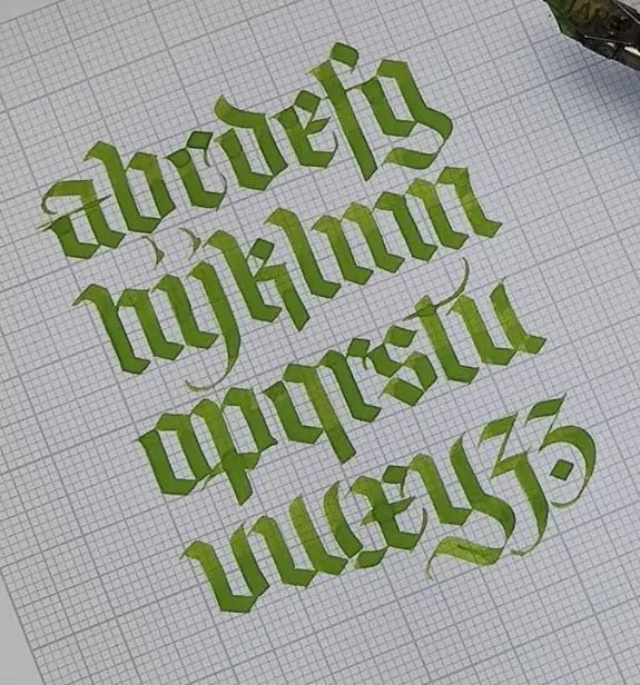 Green Blackletter lowercase alphabet on grid paper