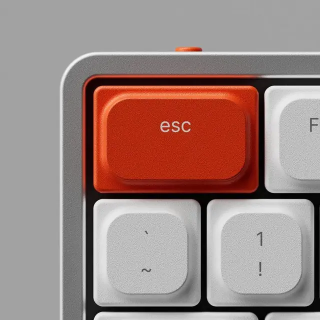 Close-up: orange ESC key on textured white/grey mechanical keyboard
