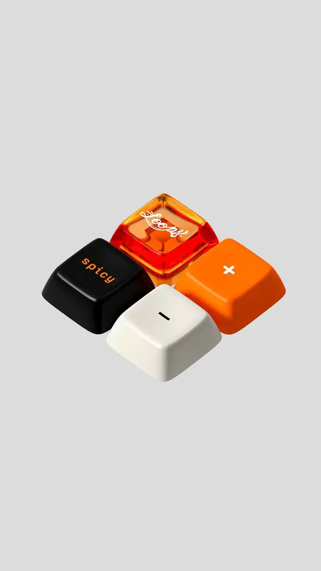 Product photo — four mechanical keyboard keycaps (black 'spicy', white '-', orange '+', AM