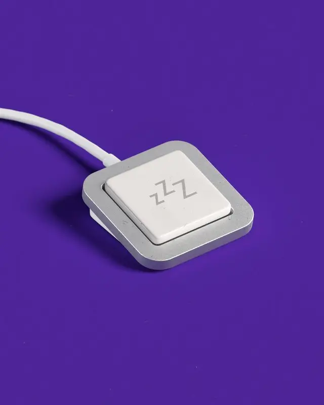 White 'zZz' sleep key on silver rounded-square base, purple backdrop