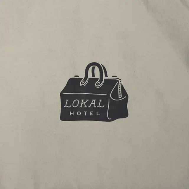 Lokal Hotel duffel bag logo — vintage travel branding on textured paper