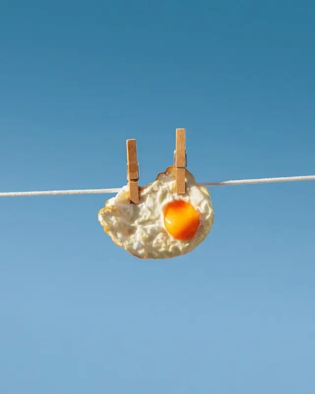 Sunny-side up egg clipped to a clothesline against clear blue sky