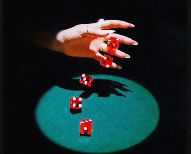 Red dice mid-air over green felt spotlight