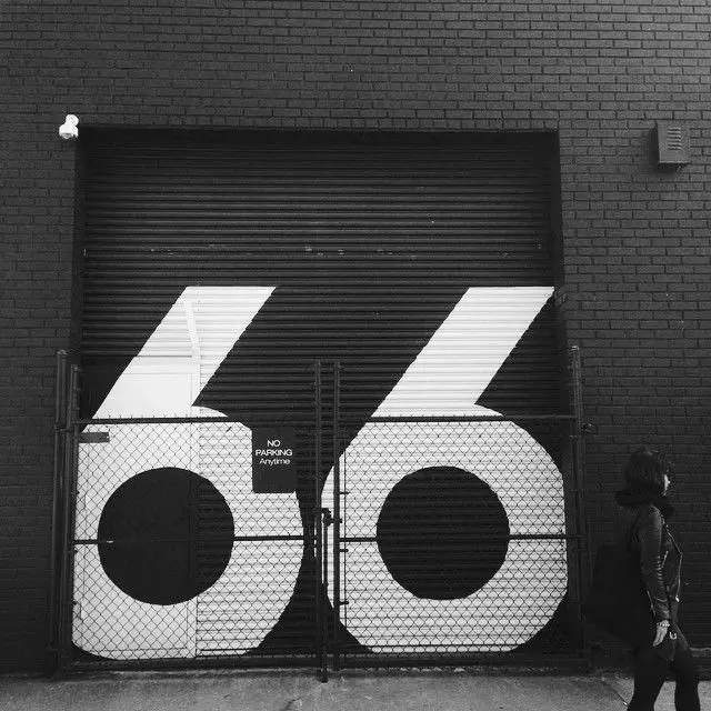 Oversized '66' painted across industrial roll-up doors with chain-link gate