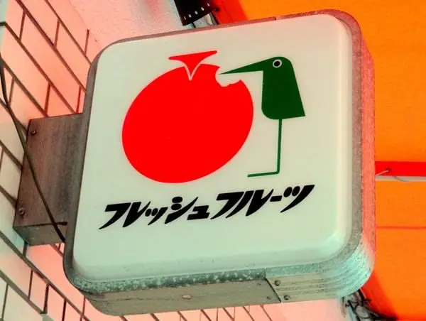 Illuminated Japanese fruit-shop sign with red fruit and green bird logo