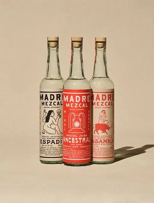 Three Madre Mezcal bottles with illustrated labels (Espadín, Ancestral, Ensamble)