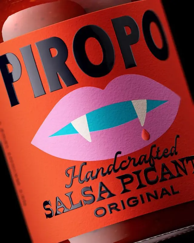 PIROPO hot sauce label — pink lips with fangs on orange textured paper