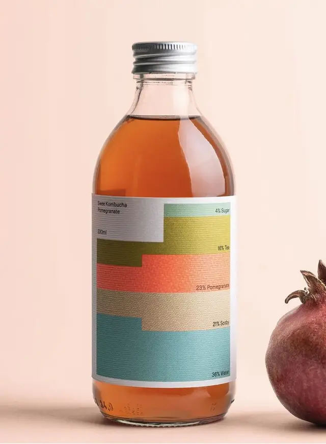 Kombucha bottle with pastel stacked-bar ingredient label and pomegranate