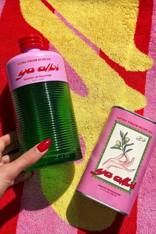 Pink-labelled Extra Virgin Olive Oil tins on colorful beach towel