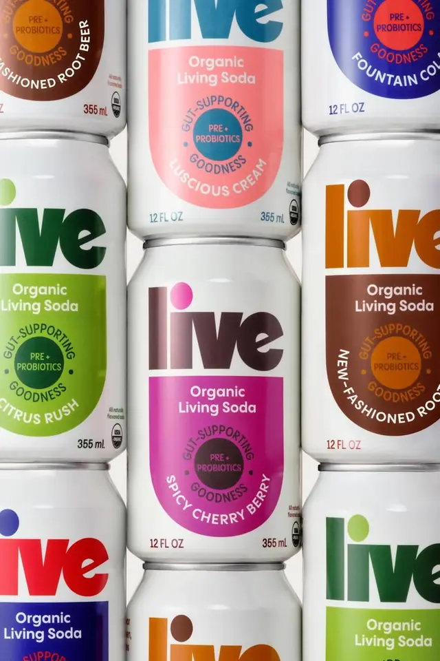 Close-up of stacked 'live' Organic Living Soda cans — colorful flavor labels and probiotic