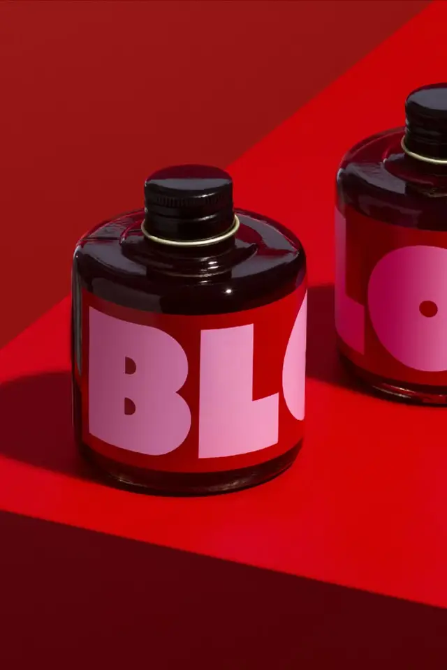 Round red glass bottles with bold pink 'BLO' label on red studio backdrop