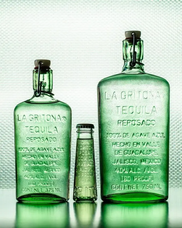 Backlit green La Gritona tequila bottles — embossed glass still life