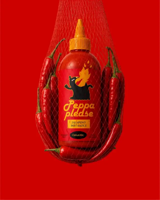 Peppa Please jalapeño hot sauce — red squeeze bottle with yellow cap and chili net