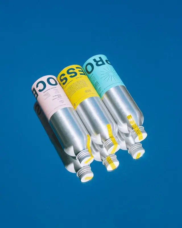 Three aluminum cartridges with pastel labels on cobalt blue background