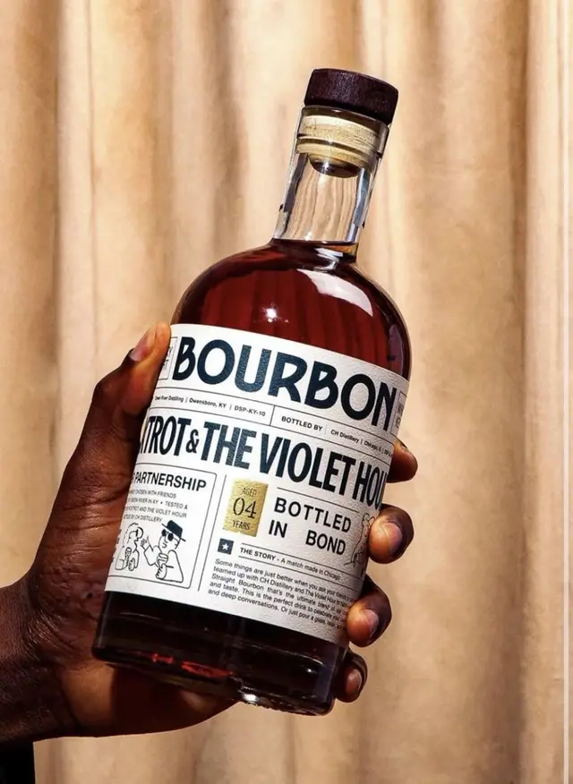 Hand-held bourbon bottle with newspaper-style label
