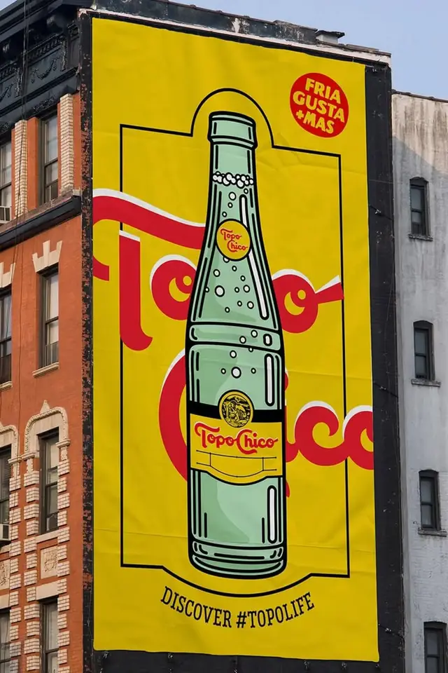 Topo Chico billboard — large yellow mural with illustrated glass bottle