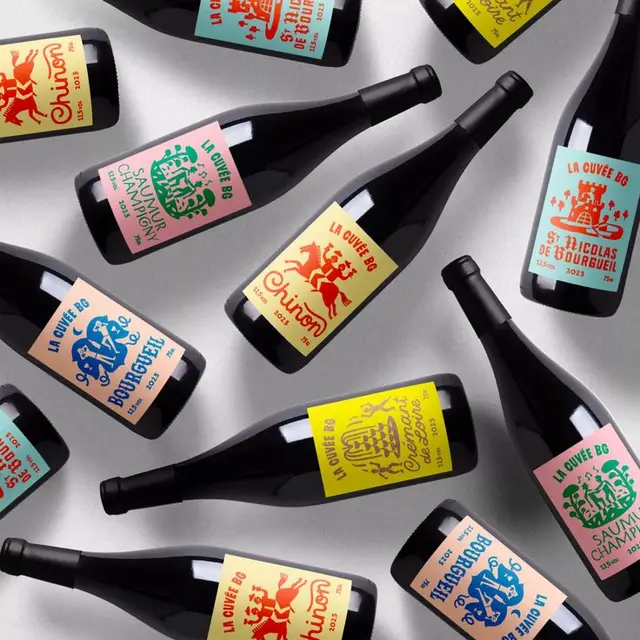 Overhead product shot — La Cuvée BG wine bottles with colorful illustrated labels