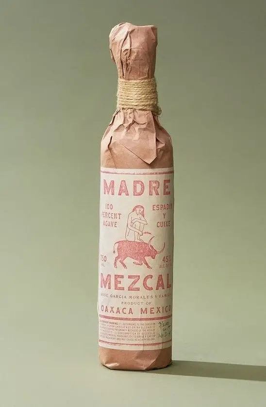 Madre Mezcal — kraft‑paper wrapped bottle with twine and pink letterpress label