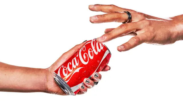 Coca‑Cola red can held between two hands — studio product shot