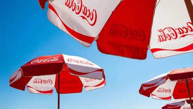 Coca‑Cola red-and-white branded umbrellas against clear blue sky
