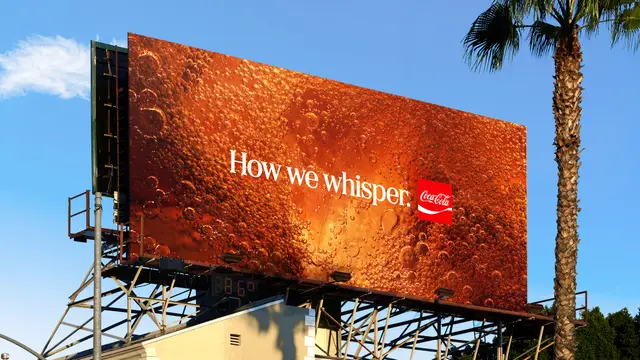 Coca‑Cola billboard — "How we whisper." over macro cola bubbles