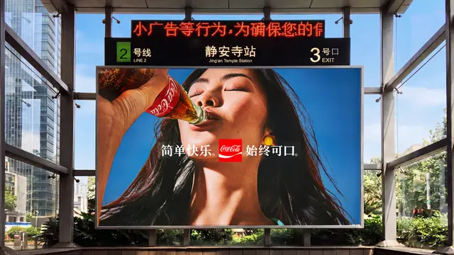 Coca‑Cola billboard at Jing'an Temple Station featuring woman drinking from glass bottle
