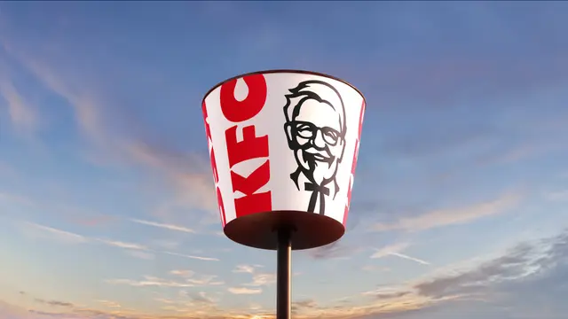 KFC bucket-shaped roadside sign on pole at sunset