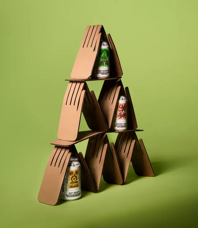 Stacked aluminum beverage cans in corrugated cardboard carriers on green backdrop