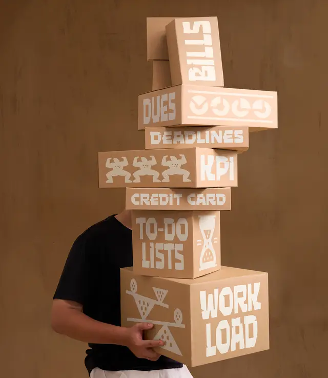 Stacked cardboard boxes labeled WORKLOAD, TO-DO LISTS, DEADLINES — conceptual packaging/st