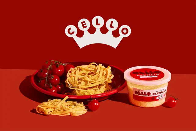 CELLO Parmesan tub with tagliatelle and vine tomatoes on red backdrop