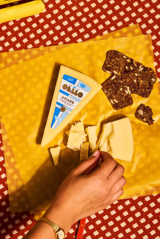 Top-down still life of Cello Asiago wedge on yellow wax paper