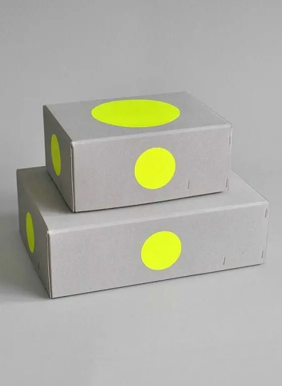 Stacked gray folding boxes with neon yellow circular stickers
